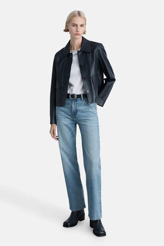 Jean droit bleu clair de MANGO porté avec une ceinture, un T-shirt blanc et une veste en cuir bleu foncé.