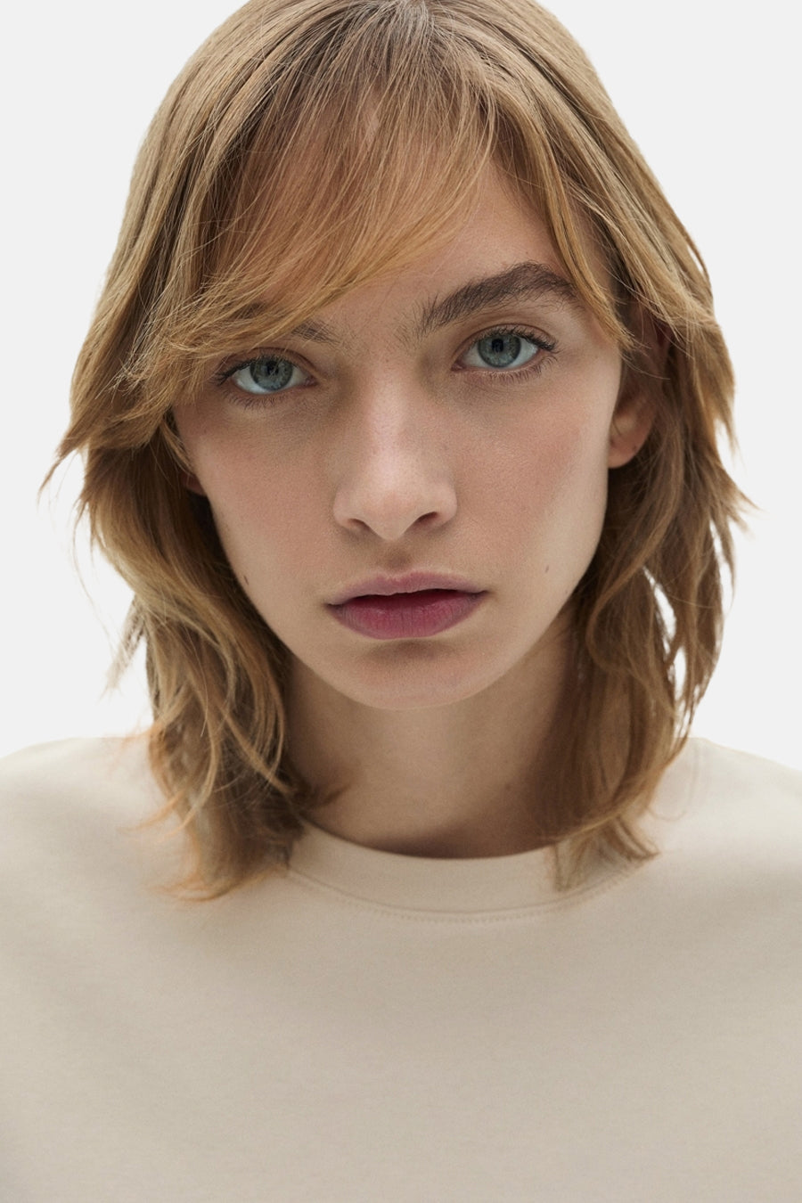 T-shirt beige à manches courtes de MANGO, gros plan d'une femme avec les cheveux détachés.