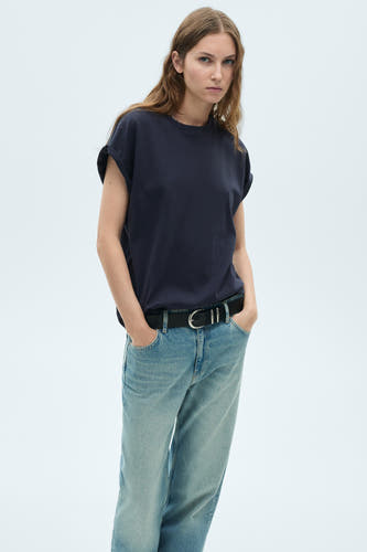 T-shirt bleu marine à manches courtes de MANGO, avec des manches retroussées, associé à un jean bleu.
