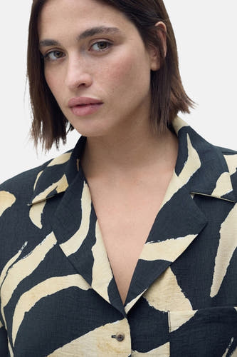 Chemise noire à manches courtes de MANGO, avec un motif zébré beige et noir.