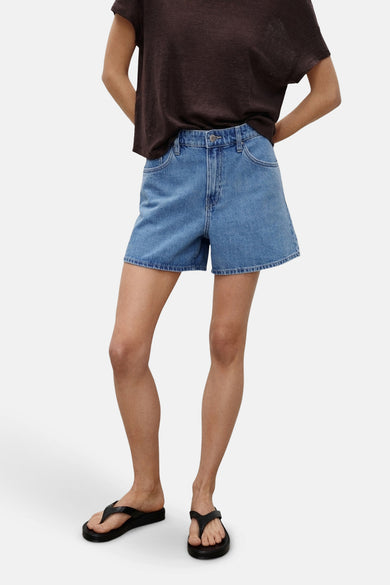 Shorts en denim bleu marine de MANGO, associés à un T-shirt marron et des pantoufles noires.