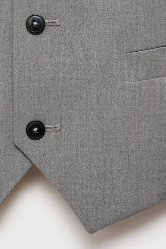 Gilet gris de MANGO, avec des boutons noirs et un petit poche poitrine.