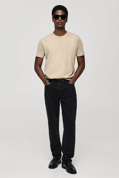 T-shirt beige à manches courtes de MANGO, porté avec des jeans noirs et des loafers en cuir.