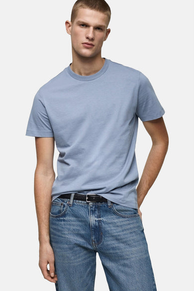 T-shirt bleu à manches courtes de MANGO, porté avec des jeans et une ceinture noire.