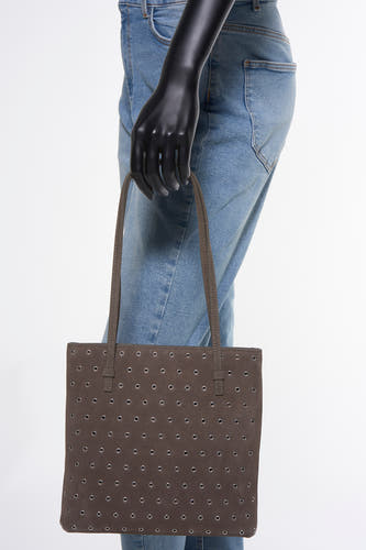 Sac à main marron de MANGO, avec des yeux décoratifs argentés, porté sur l'épaule, associé à un jean bleu.