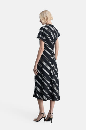 Zwarte mouwloze jurk van MANGO, met diagonale witte strepen en strappy zwarte hakken.
