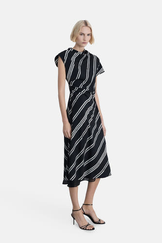 Robe sans manches noire de MANGO, avec des rayures blanches diagonales et des talons aiguilles noirs.
