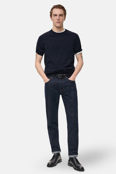 T-shirt bleu marine à manches courtes de MANGO, avec un sous-vêtement blanc et des jeans foncés avec une ceinture noire.