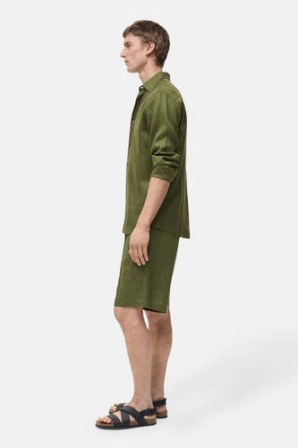 Short vert de MANGO, porté avec un chemisier en lin vert et des sandales noires, en vue latérale.