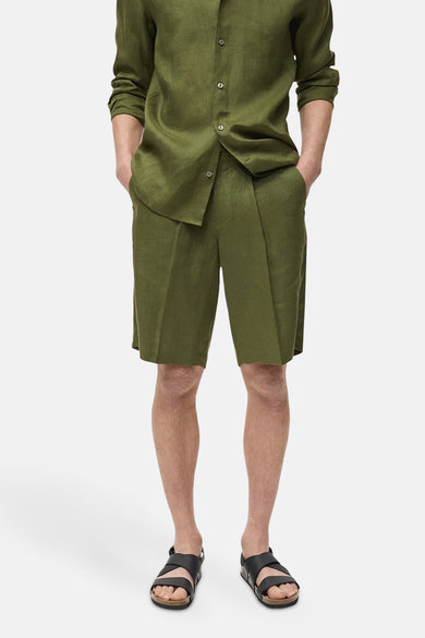 Short vert de MANGO, porté avec un chemisier en lin coordonné et des sandales noires.
