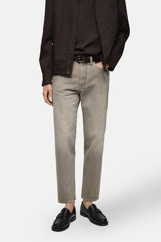 Jean tapered de MANGO en denim gris moyen, associé à une ceinture brune et des loafers noirs en cuir.