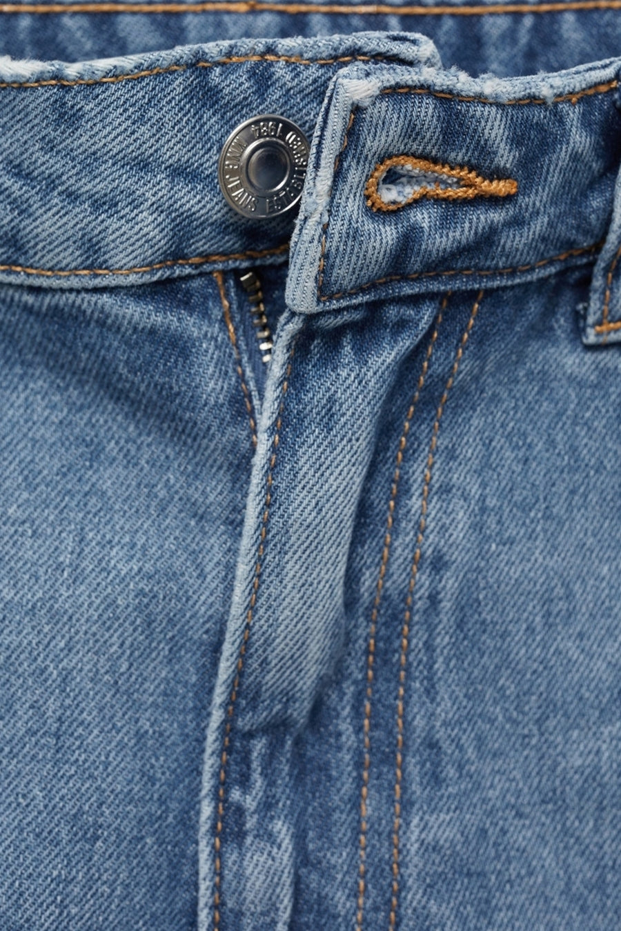 Close-up van een blauwe jeans met een zilveren knoop en een rits.