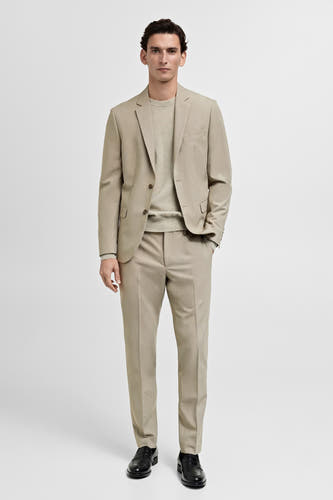 Blazer beige de MANGO, porté avec un pantalon coordonné et une chemise repassée.