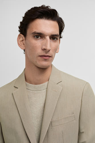 Blazer beige de MANGO, avec une fine texture et un t-shirt subtil et coordonné en dessous.