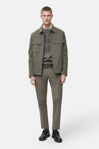 Pantalon vert de MANGO, avec des poches cargo, associé à un chemisier gris et une veste olive.