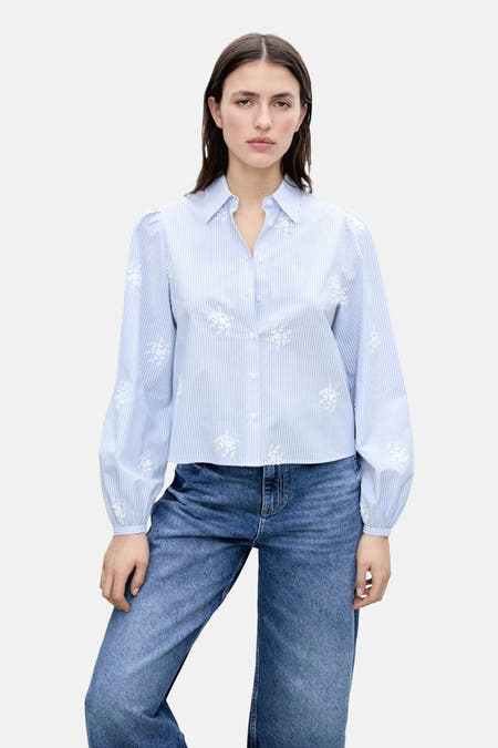 Chemise bleue à rayures avec des manches longues de MANGO, avec des motifs de fleurs blanches, associée à des jeans larges.