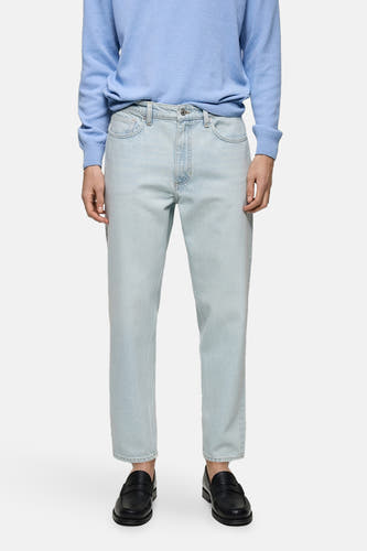 Jean en denim bleu clair tapered de Mango, avec un étiquette en cuir brun sur la ceinture, à l'arrière.