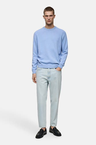 Jean tapered bleu clair de MANGO, associé à une chemise bleu clair et des chaussures noires.