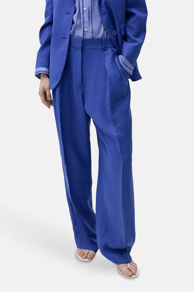 Pantalon de costume bleu MANGO, avec des jambes larges et porté avec un blauau correspondant.