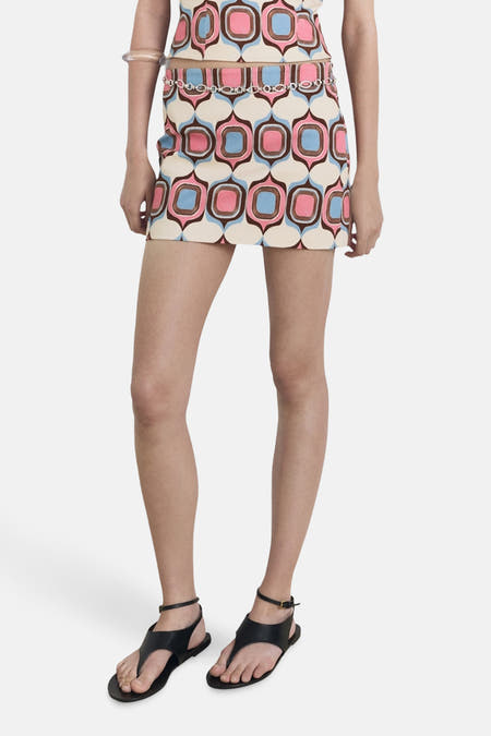 Short skirt with a retro pattern from MANGO, with a silver chain belt and black sandals.