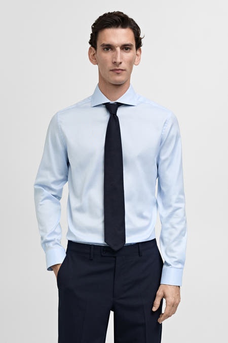Chemise bleu clair à manches longues de MANGO, portée par un homme avec une cravate bleu foncé et un pantalon.