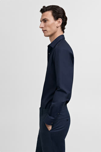 Chemise bleue à manches longues de MANGO, vue de profil d'un homme avec un pantalon assorti.