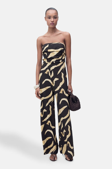 Combinaison noire de MANGO avec un motif abstrait beige, associée à un bracelet et une poche main sombre.