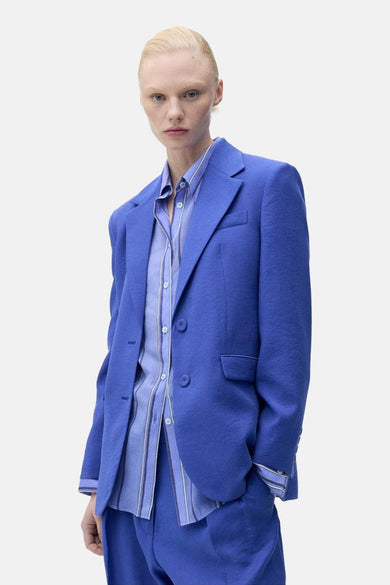 Blazer bleu de MANGO, vu de depuis l'arrière avec des manches longues et une nœud noué dans les cheveux.