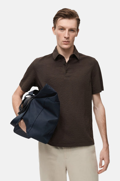 Polo marron à manches courtes de MANGO, avec une subtile texture et un col classique à l'arrière.
