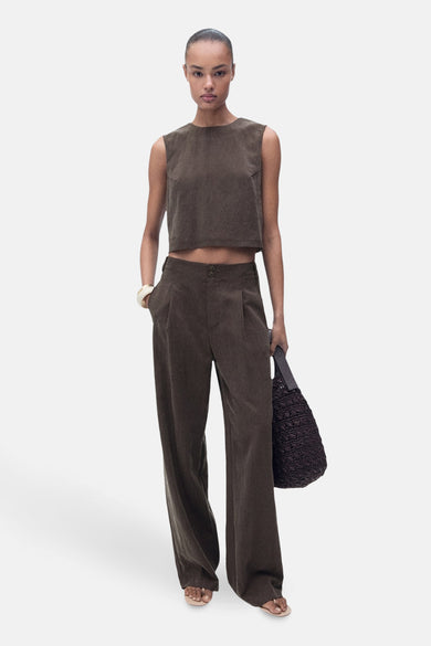 Blouse brune sans manches de MANGO, portée avec un pantalon coordonné et une sac en tricot.