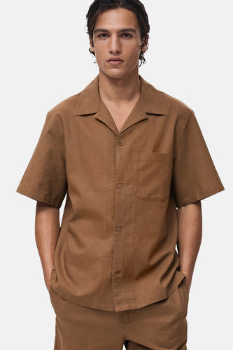 Chemise brune à manches courtes de MANGO, vue de derrière, avec un short coordonné et des sandales.