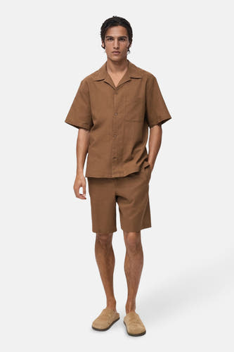 Chemise brune à manches courtes de MANGO, portée avec un short coordonné et des mocassins en cuir.