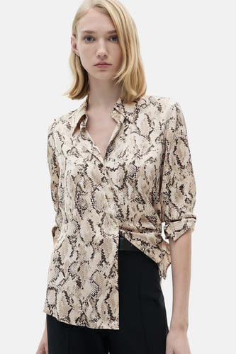 Chemise à manches longues marron de MANGO, imprimée serpent et col boutonné, associée à un pantalon noir.