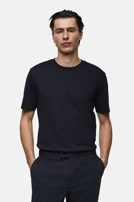 T-shirt bleu marine à manches courtes de MANGO, porté avec un pantalon foncé à poches.