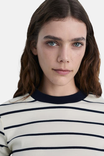 T-shirt rayé blanc (manches courtes) de MANGO, avec une encolure ronde et des cheveux ondulés brun foncé.