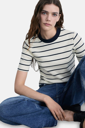 T-shirt blanc à manches courtes de MANGO, avec des rayures bleu marine et un col rond, associé à un pantalon large.