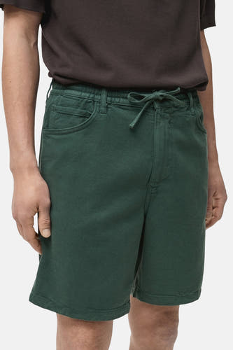 Short vert de MANGO, avec cordon et poches, porté avec un t-shirt marron.