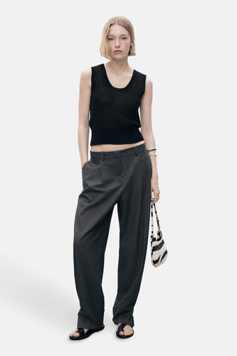 T-shirt noir de MANGO, sans manches et associé à un pantalon gris et un sac imprimé zèbre.