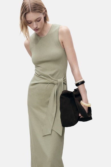Vêtement khaki sans manches de MANGO, avec détail rayé et associé à des bracelets et un sac marron foncé.