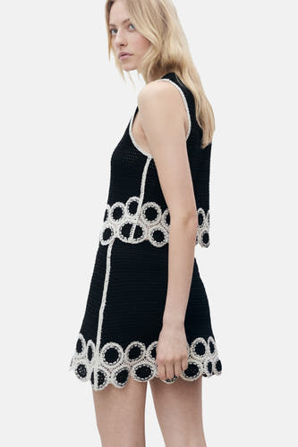 Jupe courte noire de MANGO, avec un motif de fleurs tricoté le leour et une bordure blanche verticale.