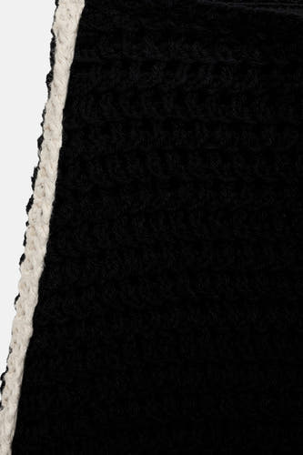 Jupe noire courte de MANGO, avec un motif tricoté et une bordure blanche sur le côté.
