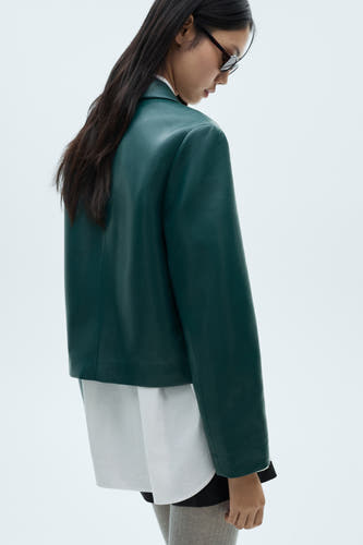 Veste bleue de MANGO, vue de l'arrière, combinée à une chemise blanche et des chaussettes grises.