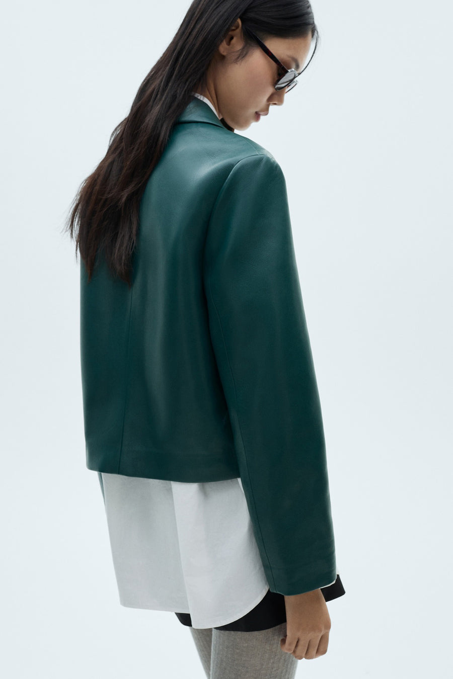 Veste bleue de MANGO, vue de l'arrière, combinée à une chemise blanche et des chaussettes grises.