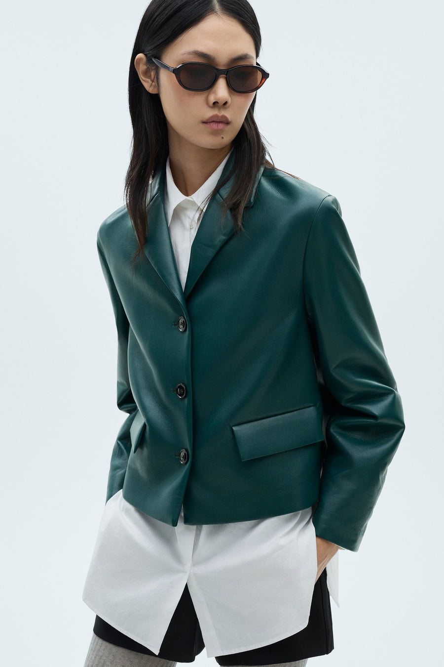 Blazer courte bleue de MANGO, à manches longues, fermeture à boutons et détail de poche.
