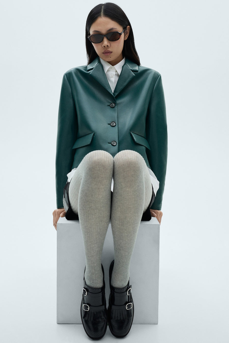 Blague courte de MANGO, à manches longues, fermeture à boutons et poches, combinée avec une chemise blanche, des chaussettes grises et des chaussures noires.