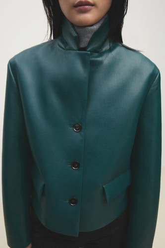Blazer courte bleu de MANGO, à manches longues, col montant et boutons noirs.