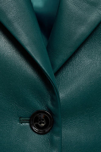 Blazer courte bleu de MANGO, avec une fermeture à un bouton et un col à revers en cuir lisse.