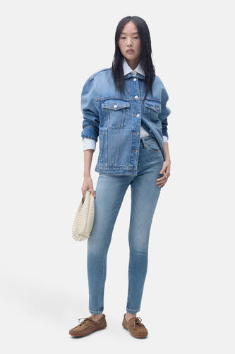 Jean skinny bleu clair en denim de MANGO, associé à un blouson en denim et des mocassins marrons.