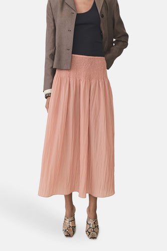 Roze midi-rok met elastische tailleband, gecombineerd met bruin jasje en slangenprint muiltjes.