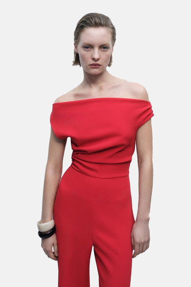 Combinaison rouge de MANGO, à épaules dénudées et à taille plissée, associée à des bracelets.